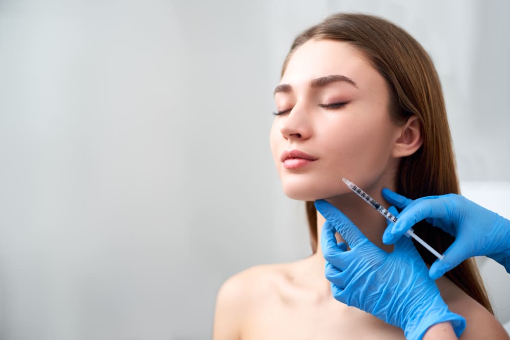 Beautiful young woman getting dermal filler injections to her chin and cheeks for a refreshed appearance.